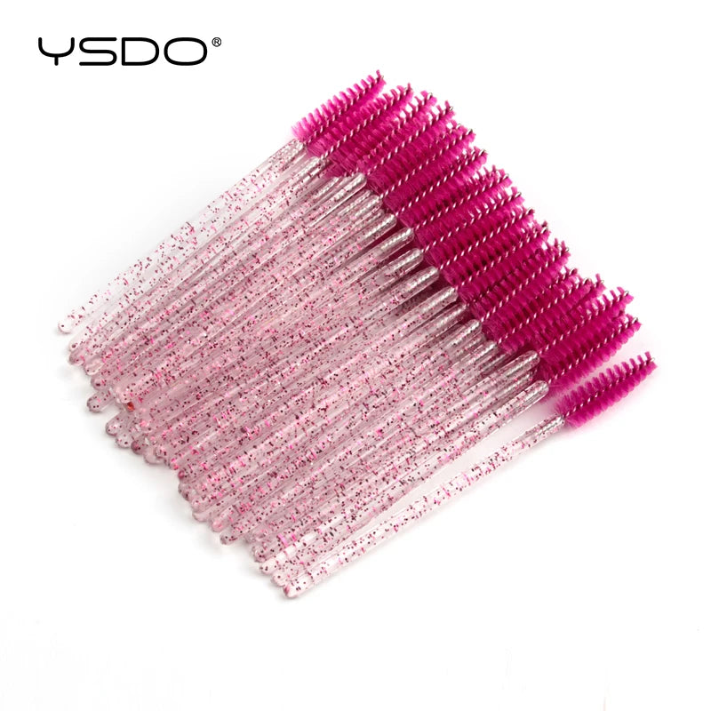Disposable eyelash spoolie brushes with bright pink heads and clear, glitter-filled plastic handles.