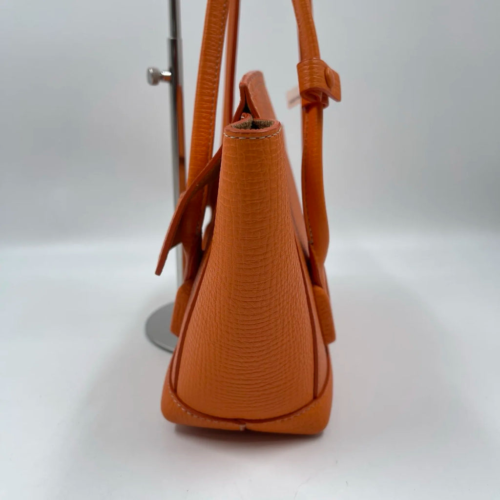 Luxury orange genuine leather designer handbag, textured tote style with two handles and flap closure.