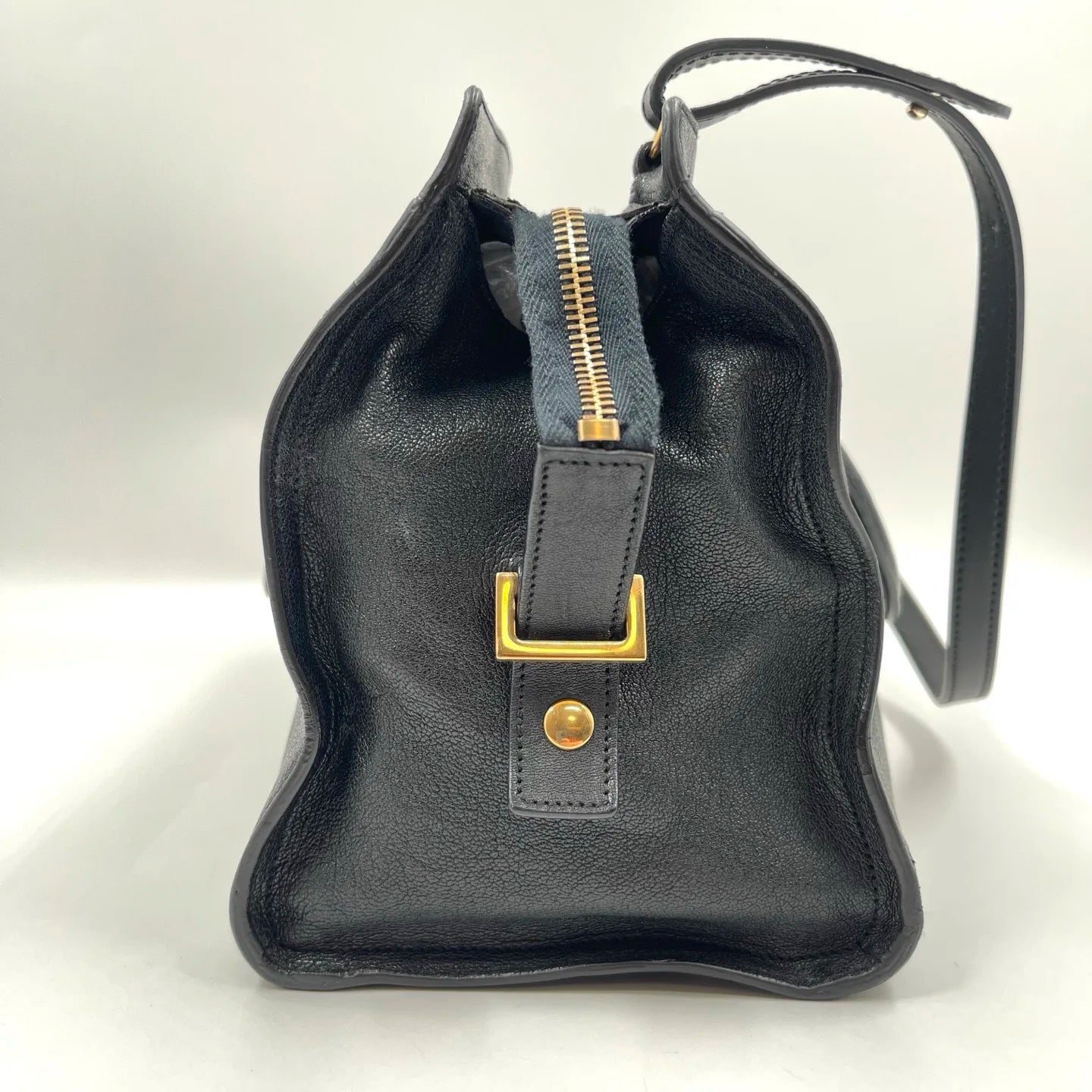 Black genuine leather designer handbag, pillow-shaped with gold hardware, top zipper, and dual straps. Retro style.