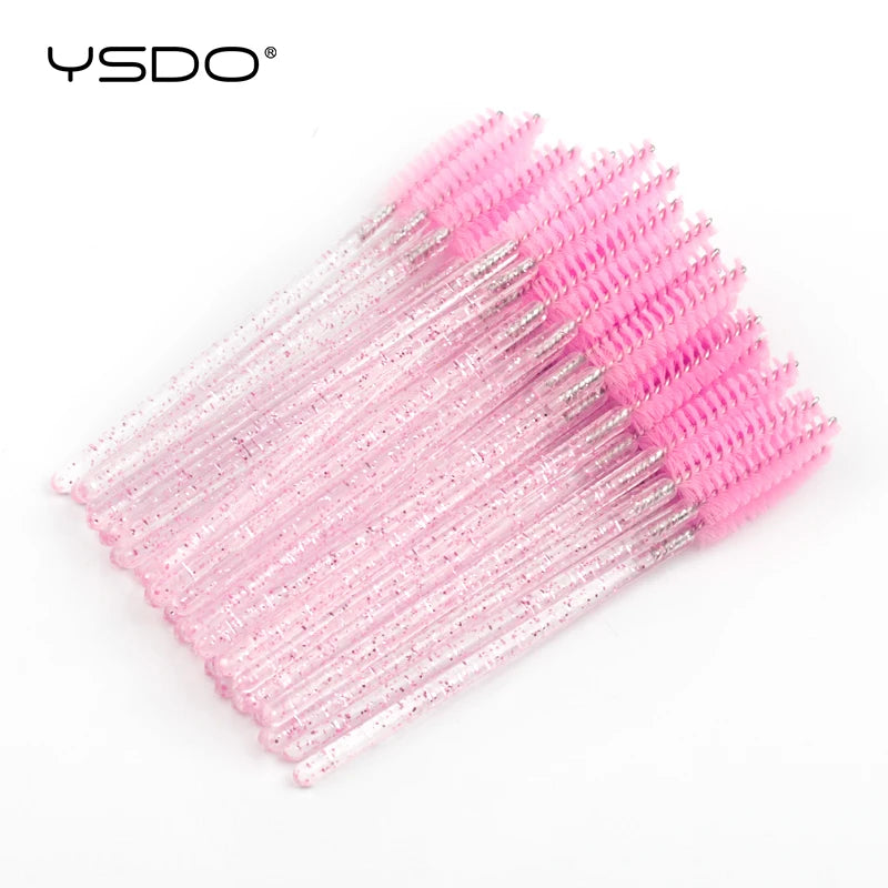 Disposable eyelash spoolie brushes with bright pink bristles and clear plastic handles filled with silver glitter.
