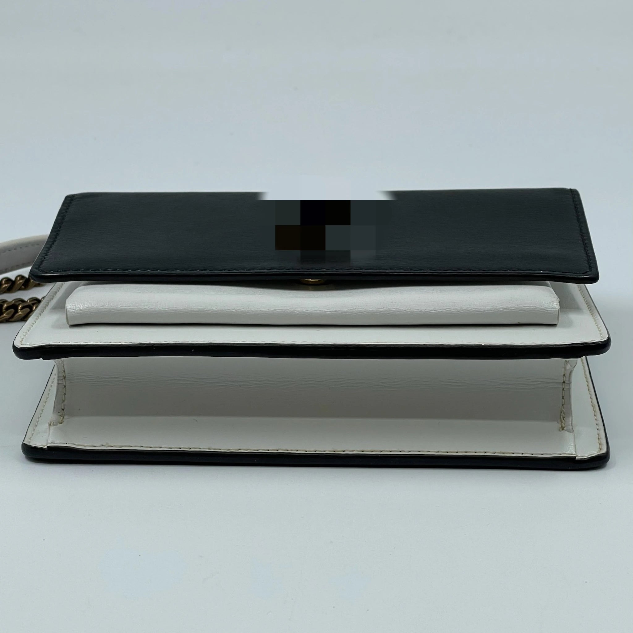 Second-hand black and white leather designer shoulder bag with a snap closure and gold-tone chain strap for parties.