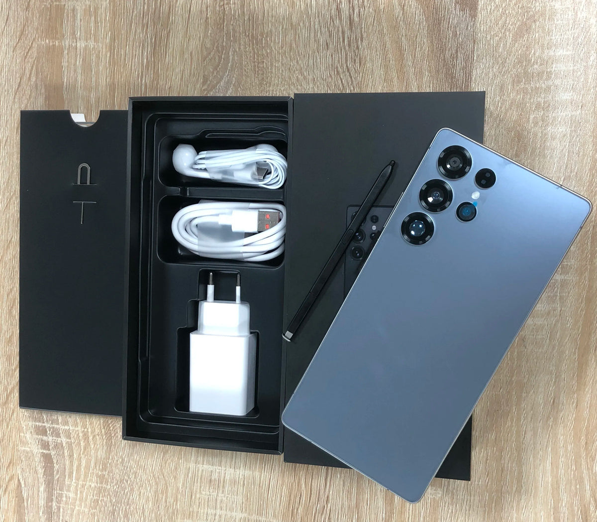 Blue-gray smartphone and retail box with bundled cables and charging adapter