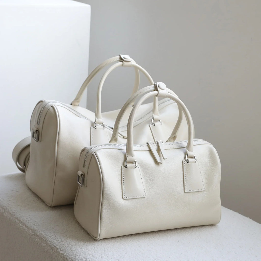 Off-white vegetable-tanned leather minimalist Boston bags with dual zip closures and large-capacity top handles.