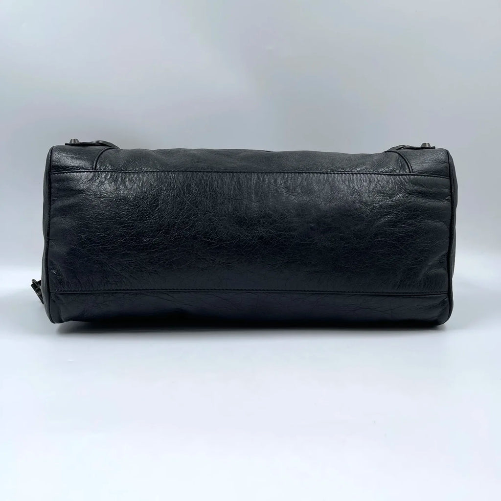 Black genuine leather designer handbag, pillow-shaped tote with tassel detail, stylish luxury second-hand accessory.
