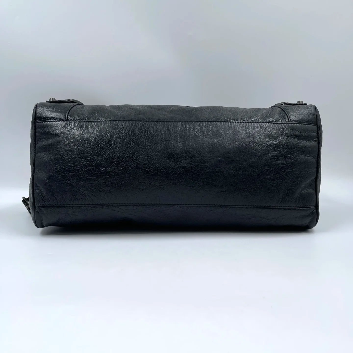 Black genuine leather designer handbag, pillow-shaped tote with tassel detail, stylish luxury second-hand accessory.