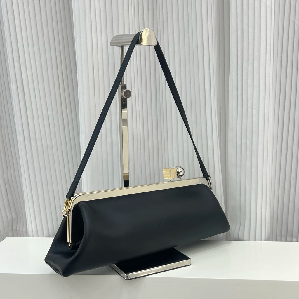 Black leather designer shoulder bag with a sleek frame, silver clip closure, and minimalist long silhouette.
