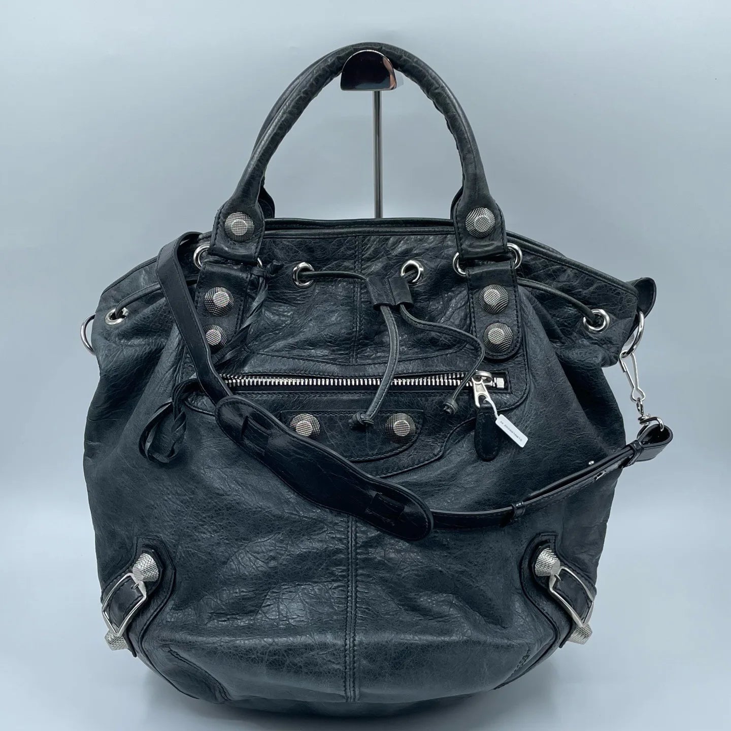 Pre-owned black leather designer bucket bag with metal studs, top handle, zip pocket, and adjustable shoulder strap.