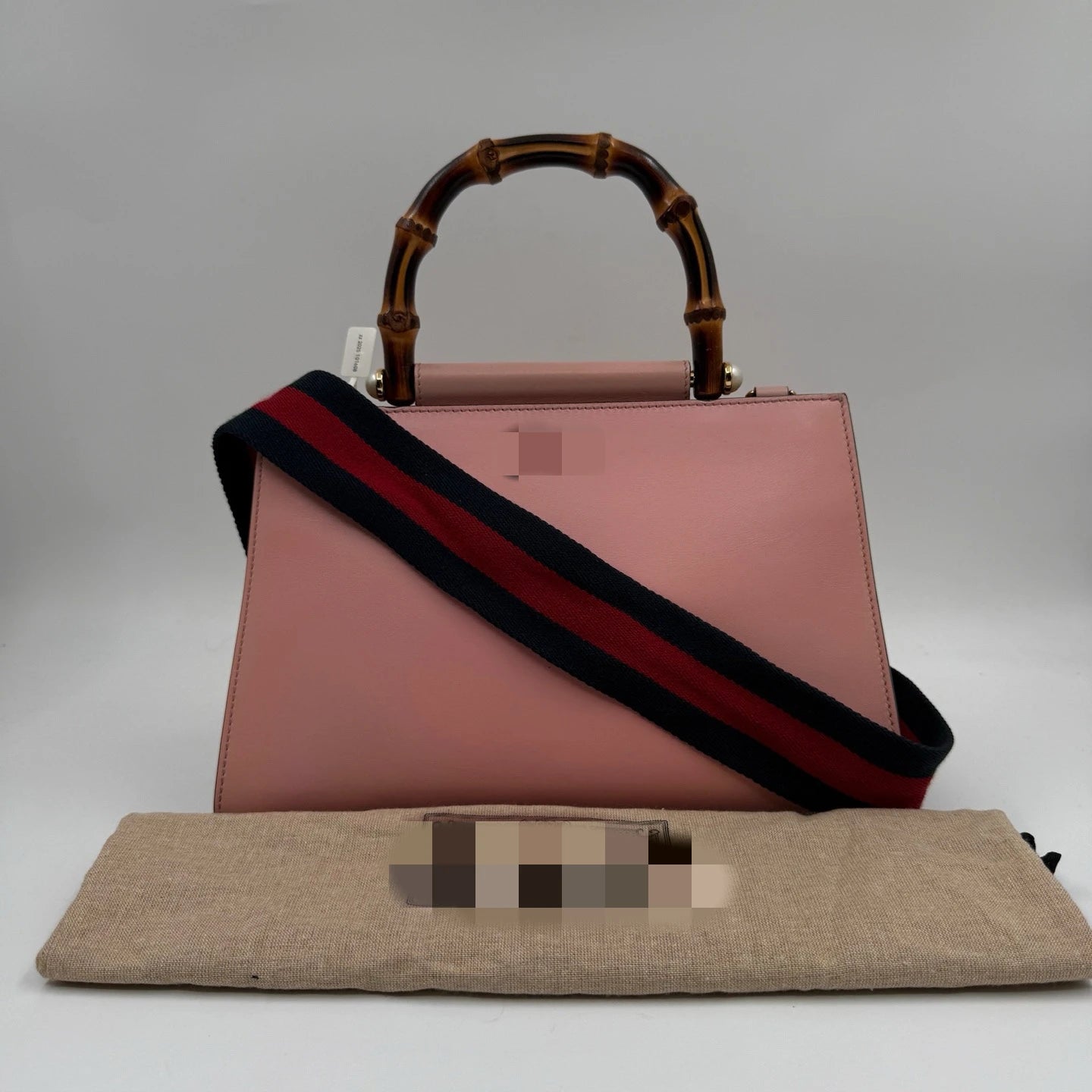 Pre-owned pink leather designer handbag with bamboo handle and detachable navy and red striped shoulder strap.
