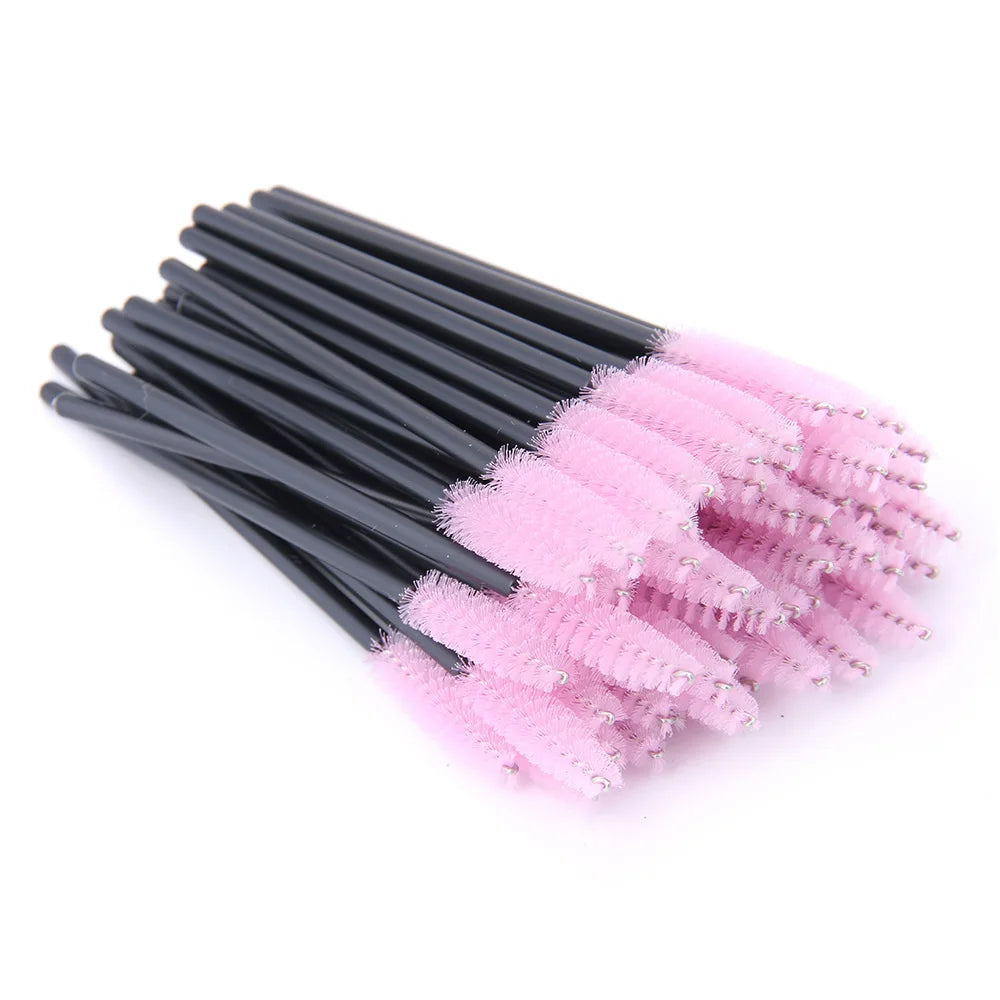 A bundle of disposable eyelash brushes with black plastic handles and soft, pink nylon spoolie heads.