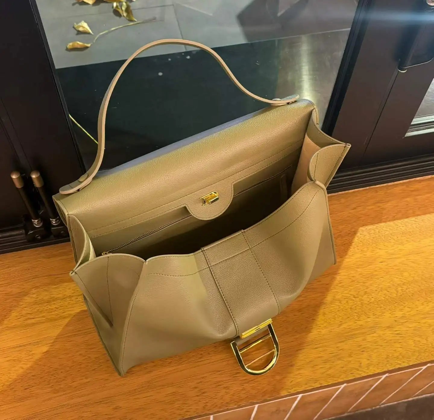 Olive green leather designer shoulder bag with a large structured tote silhouette and gold hardware clasp.
