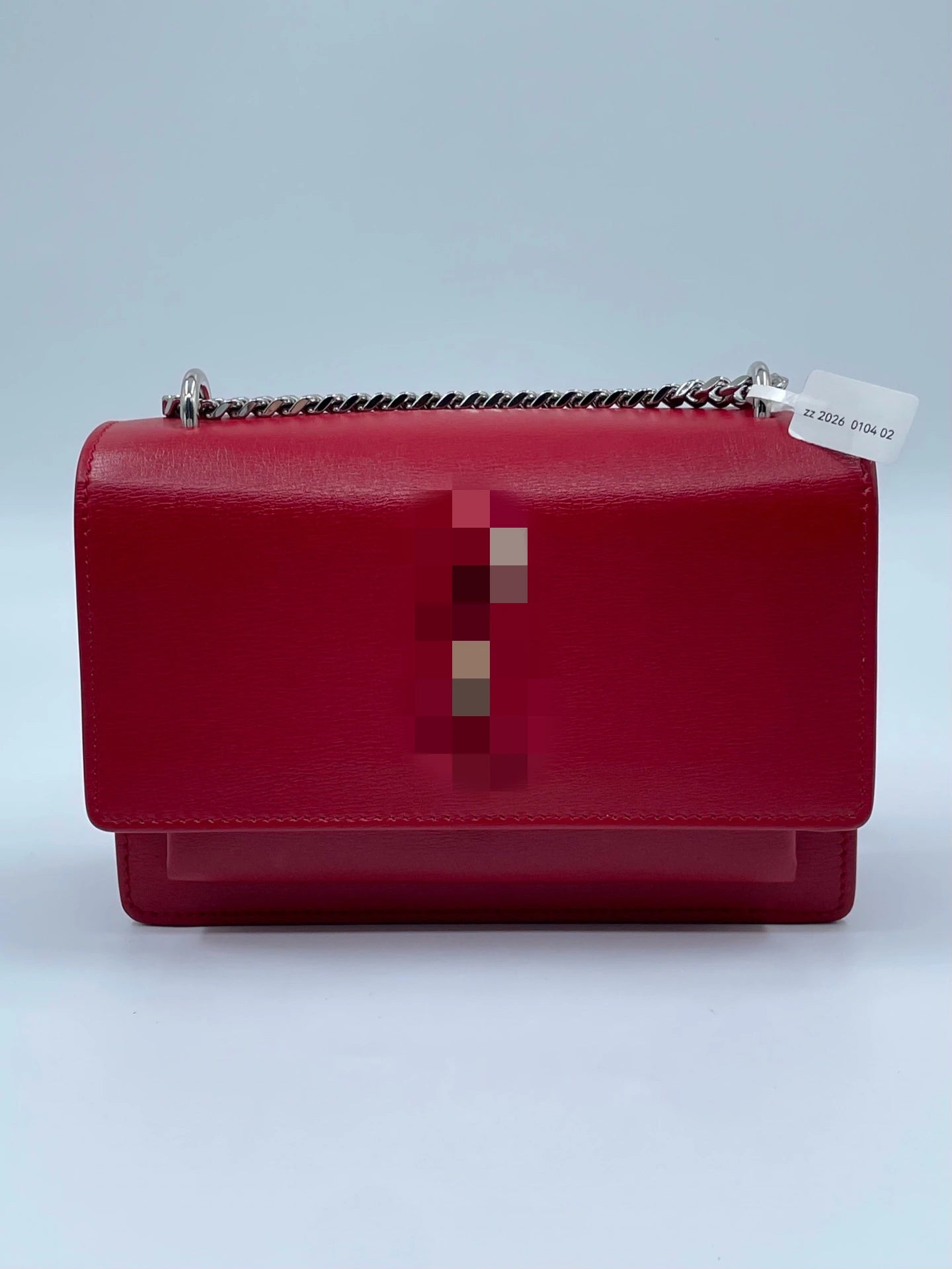 Red genuine leather designer crossbody bag with silver chain strap and structured elegant silhouette.