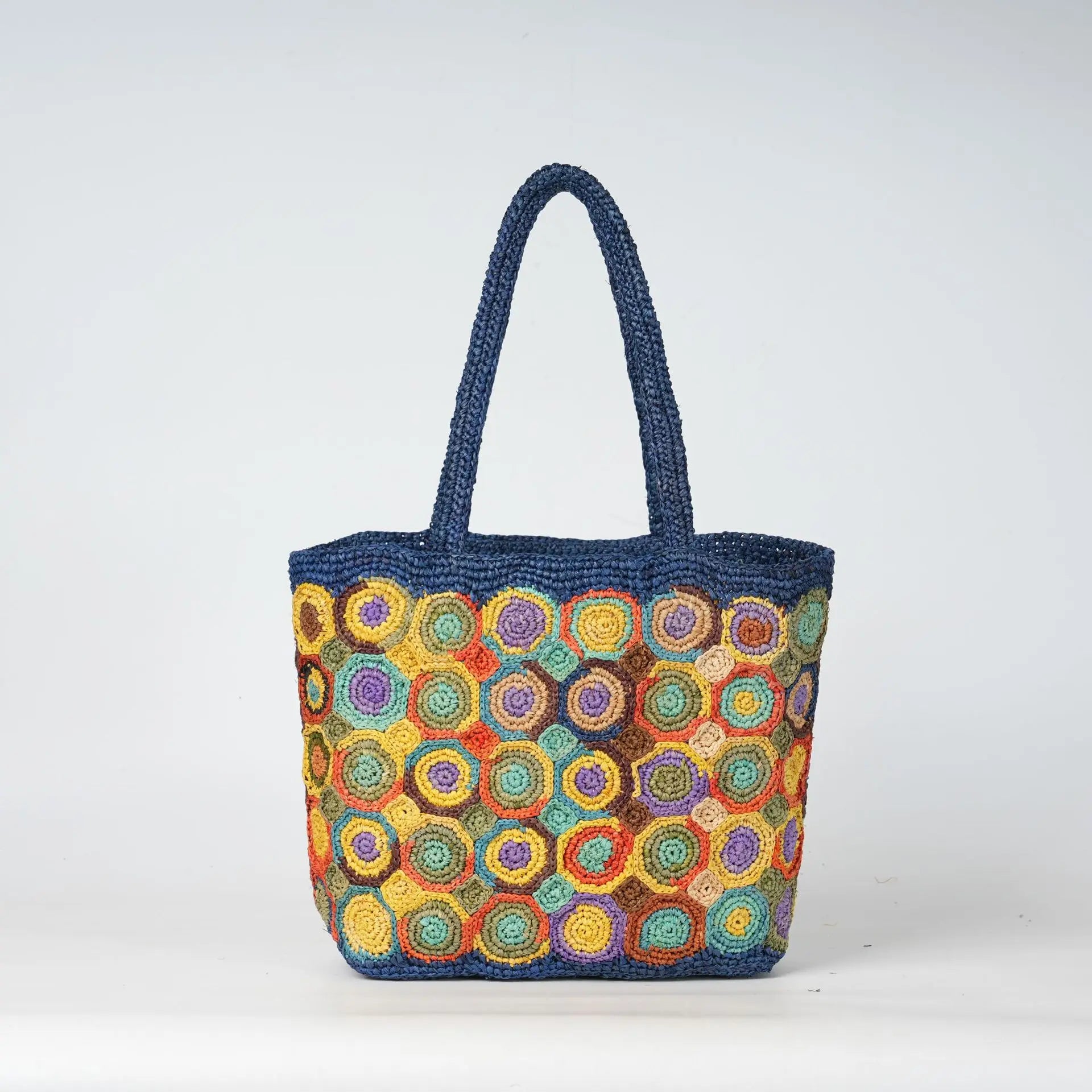 Blue woven crochet tote bag with multicolor spiral circular patterns, durable beach style ladies handbag.
