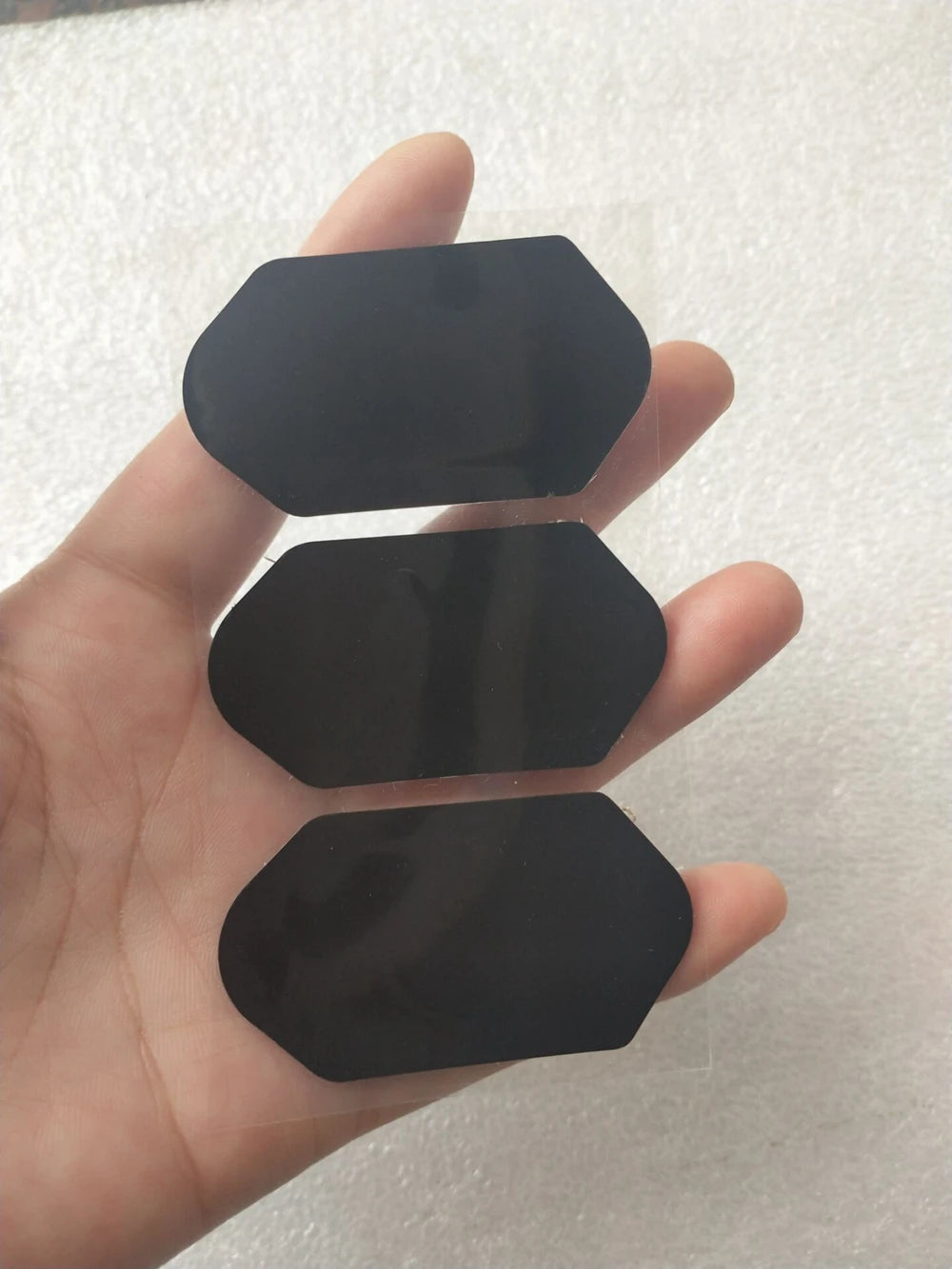 Replacement black film stickers for 3D 4D HIFU cartridge, hexagonal adhesive repair patches held in hand.