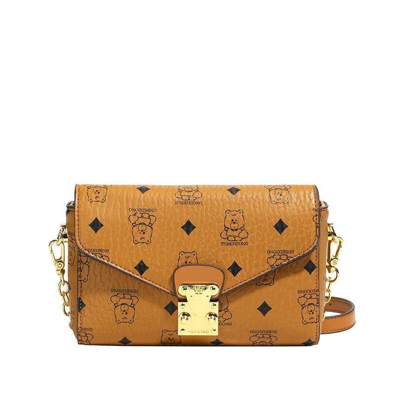 Brown genuine leather monogram envelope crossbody bag with bear print, gold hardware, and trunk-style clasp.