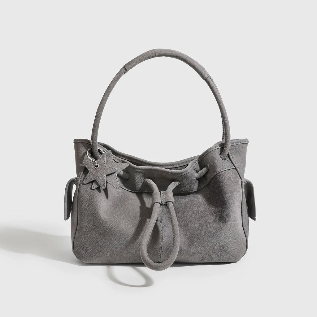 Grey textured leather underarm shoulder bag with drawstring closure, top handle, and star charm designer handbag.