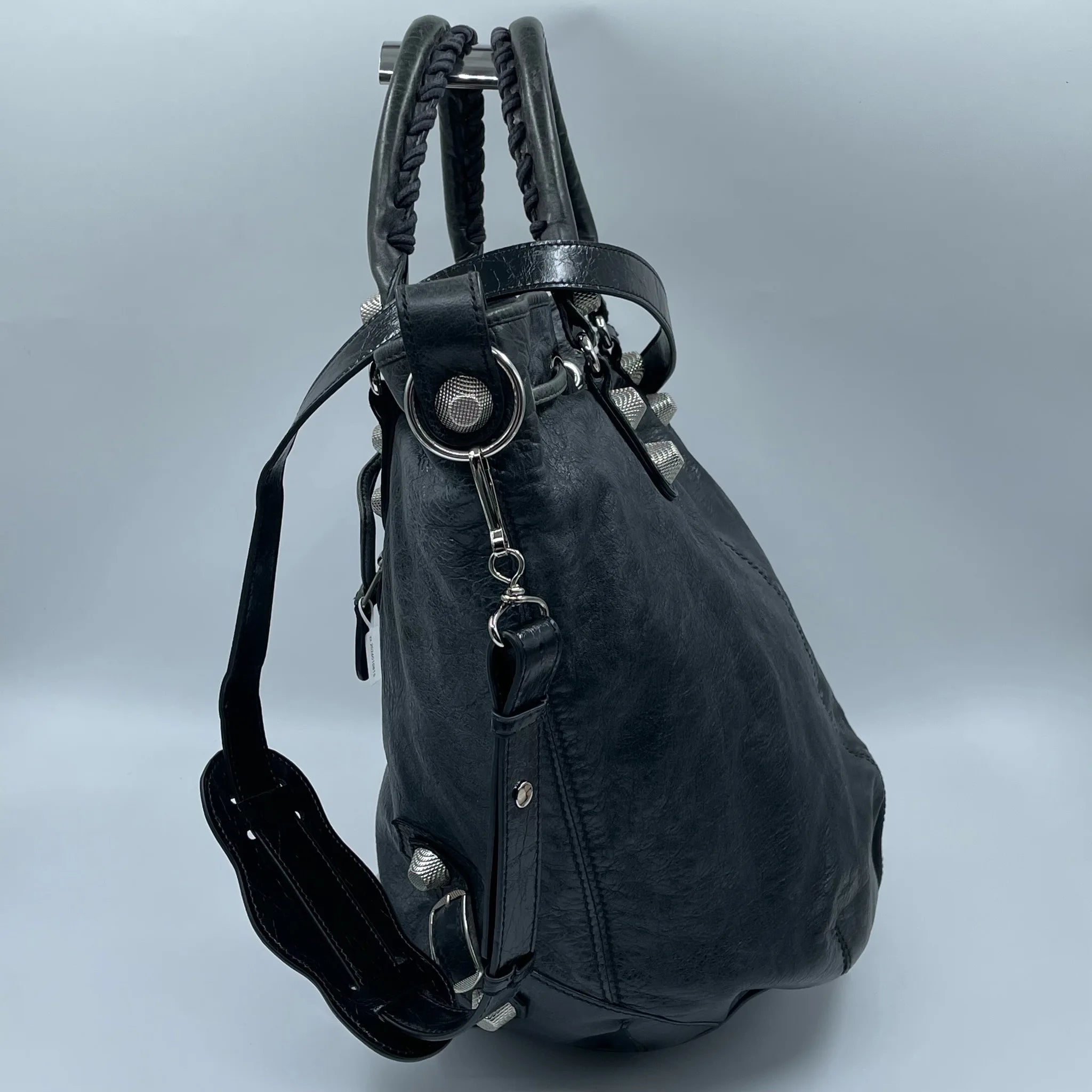 Pre-owned black leather designer bucket bag with silver metal studs, braided top handles, and adjustable shoulder strap.