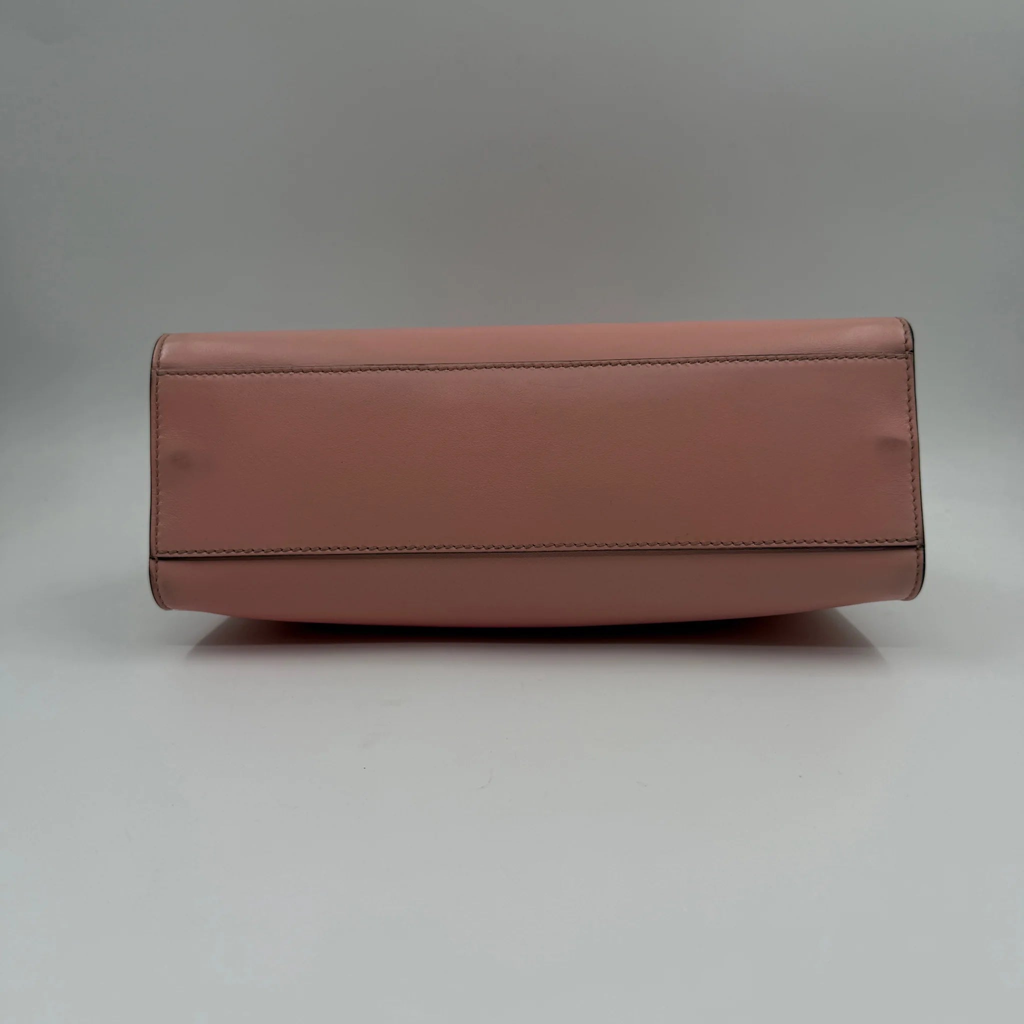 Bottom view of a luxury pre-owned pink leather designer crossbody bag with a flat, structured base.