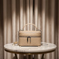 Beige quilted genuine leather trunk box bag with silver hardware, top handle, and detachable chain shoulder strap.
