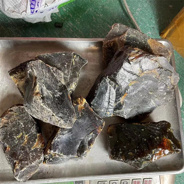 Mixed rough amber gemstone shards in a metal tray