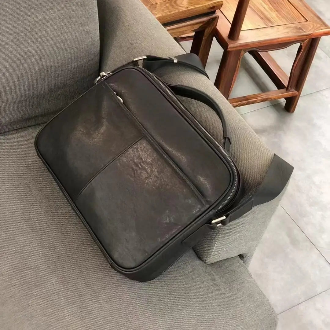 Small dark brown cowhide leather messenger bag with top handle, zip closure, and crossbody strap. Retro business style.