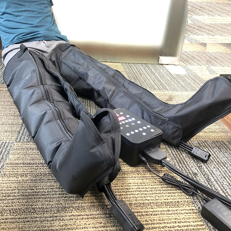 Person using black XXL air compression leg massage boots with digital controller for recovery and circulation.