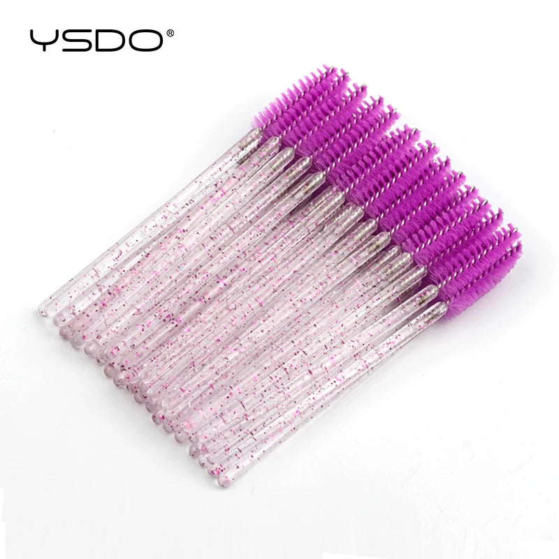 Disposable eyelash spoolie brushes with bright purple heads and clear, glitter-filled plastic handles.