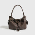 Dark brown leather underarm shoulder bag with a drawstring closure, star charm, and spacious design for commuting.