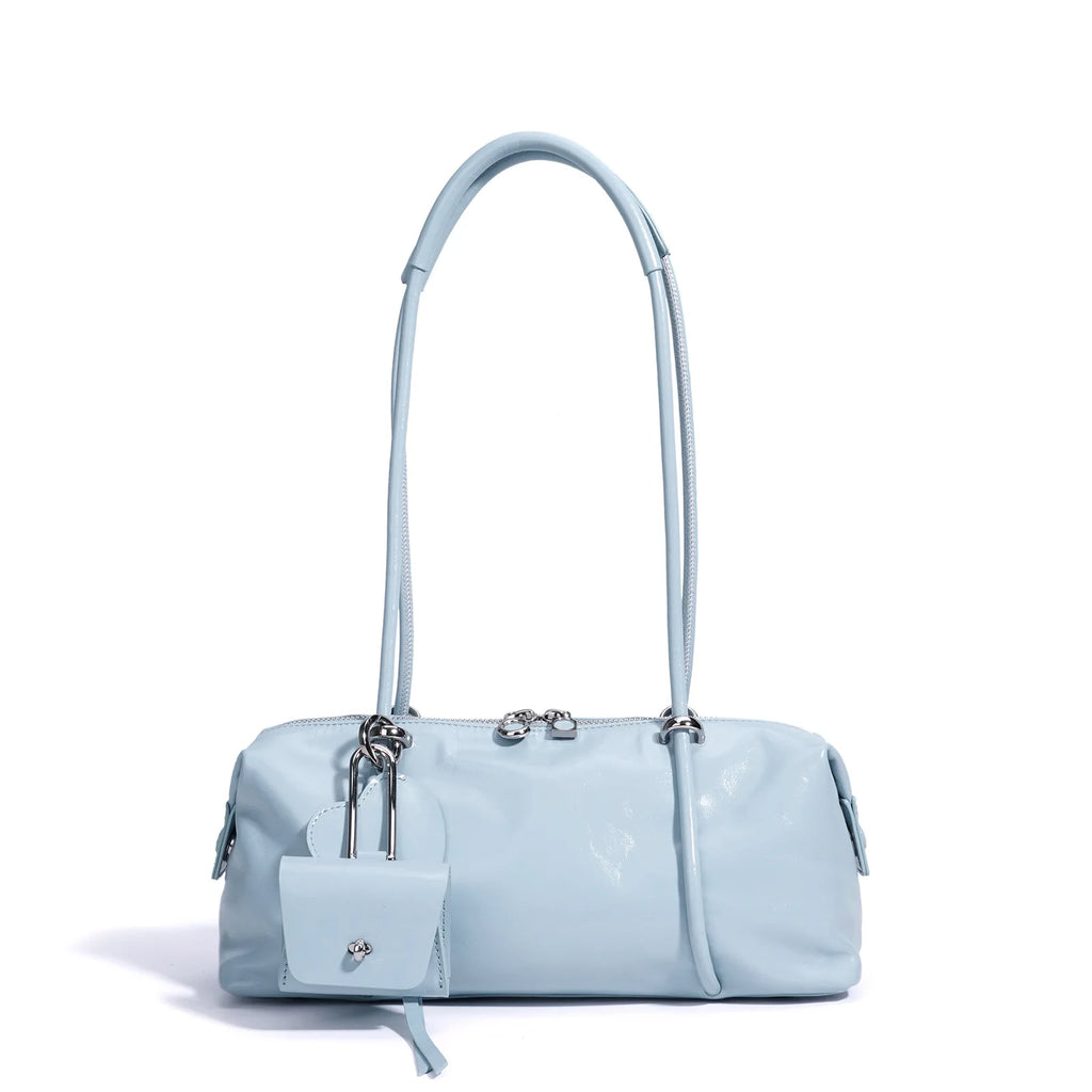 Light blue Boston underarm bag, minimalist pillow style, luxe texture with zipper closure and charm accessory.