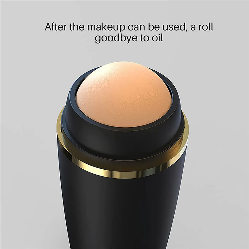 Face oil absorbing roller with a round, textured, tan volcanic stone in a matte black handle with gold trim.