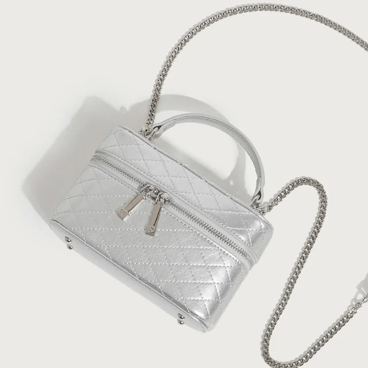 Silver quilted leather trunk box bag for women with silver chain shoulder strap and top handle.