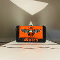 Black and orange rhinestone hard shell evening clutch with bee motif, “Queen” text, and detachable chain strap.
