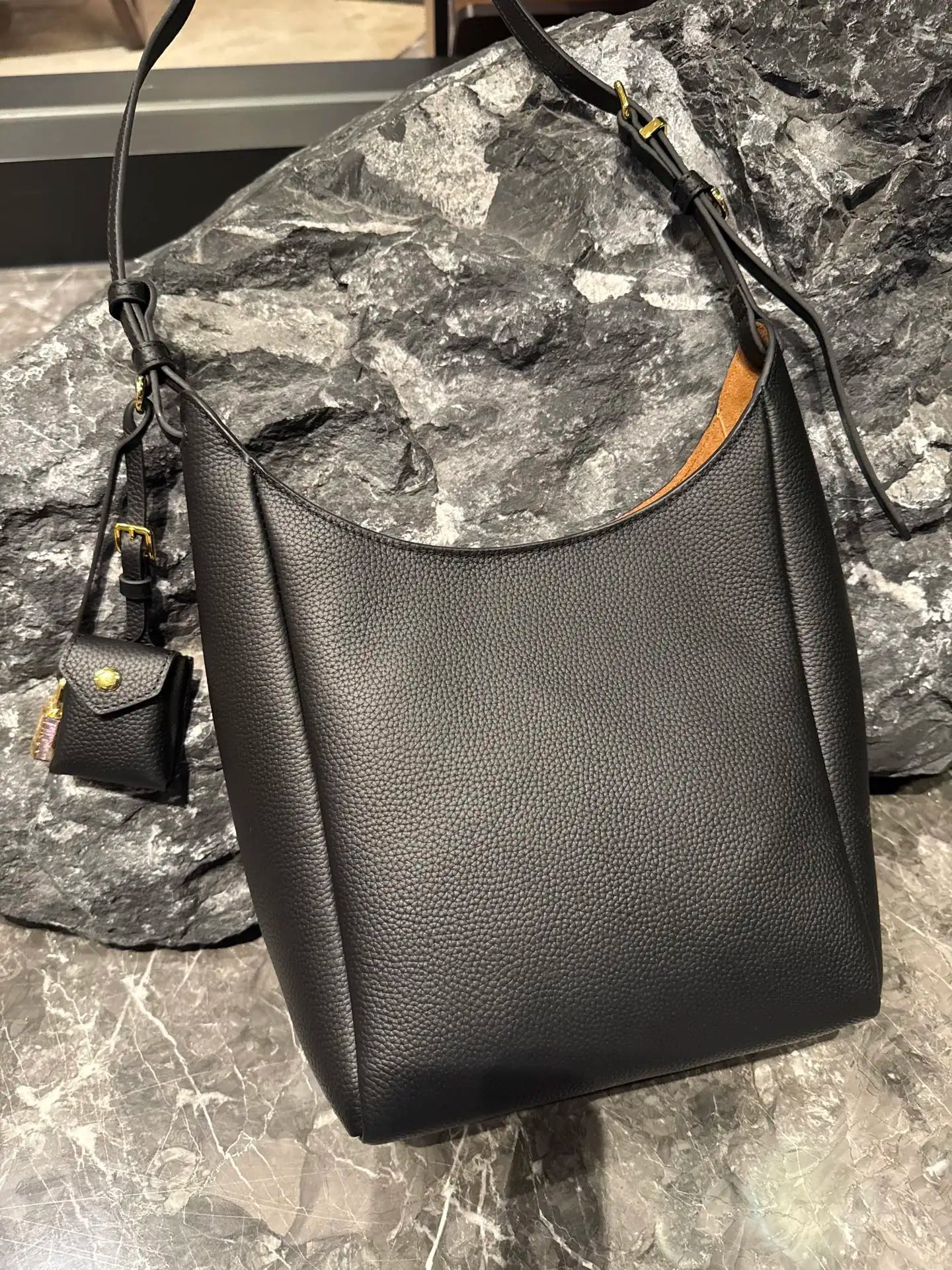 Black genuine leather hobo shoulder bag with pebble texture, adjustable strap, and small detachable pouch accessory.