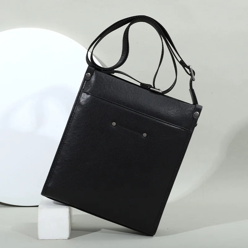 Black genuine leather business casual crossbody tote bag with slim vertical profile, adjustable strap, and rivet studs.