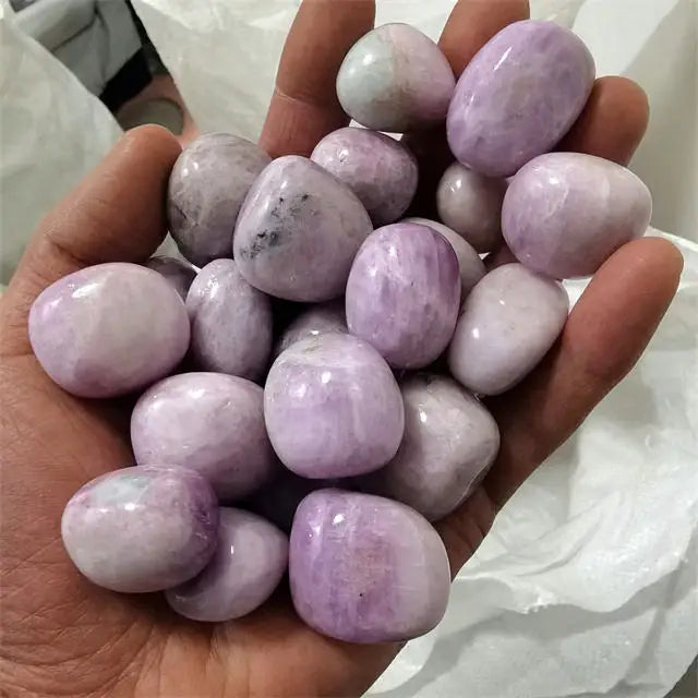 Purple kunzite tumbled stones, glossy rounded pieces in a hand