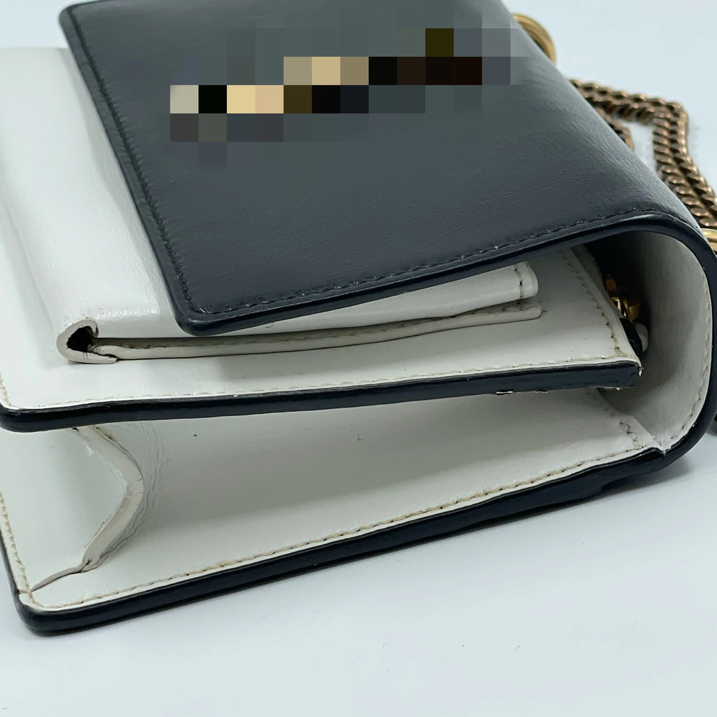 Designer black and white leather shoulder bag, second-hand luxury party purse with gold chain and snap closure.