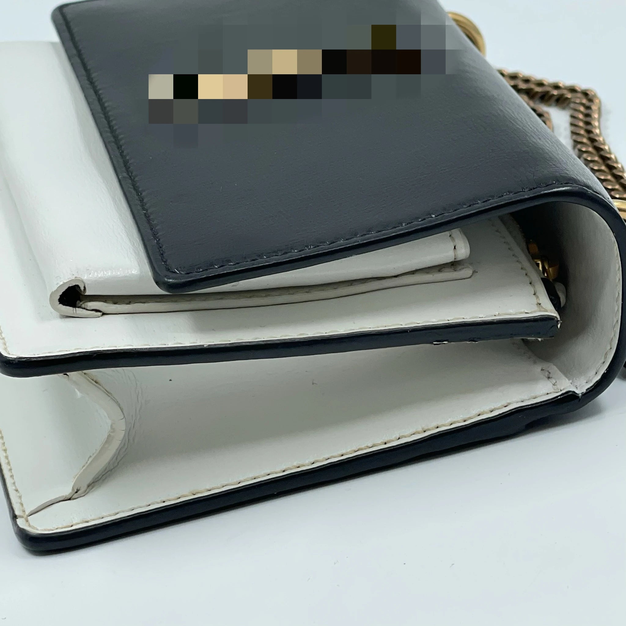 Designer black and white leather shoulder bag, second-hand luxury party purse with gold chain and snap closure.