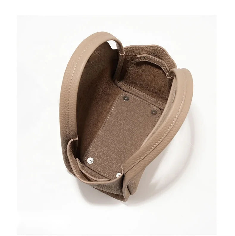 Taupe pebble leather designer handbag, open interior view with top handles and protective base studs.
