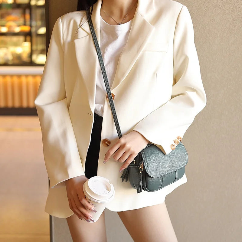 Dark green genuine leather designer crossbody bag with a flap, tassel detail, and adjustable shoulder strap.