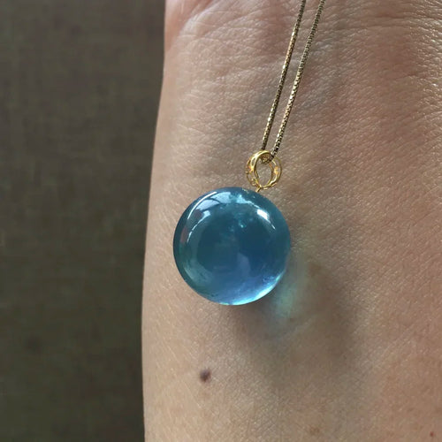 Blue round bead pendant necklace worn on skin, gold-tone chain and bail