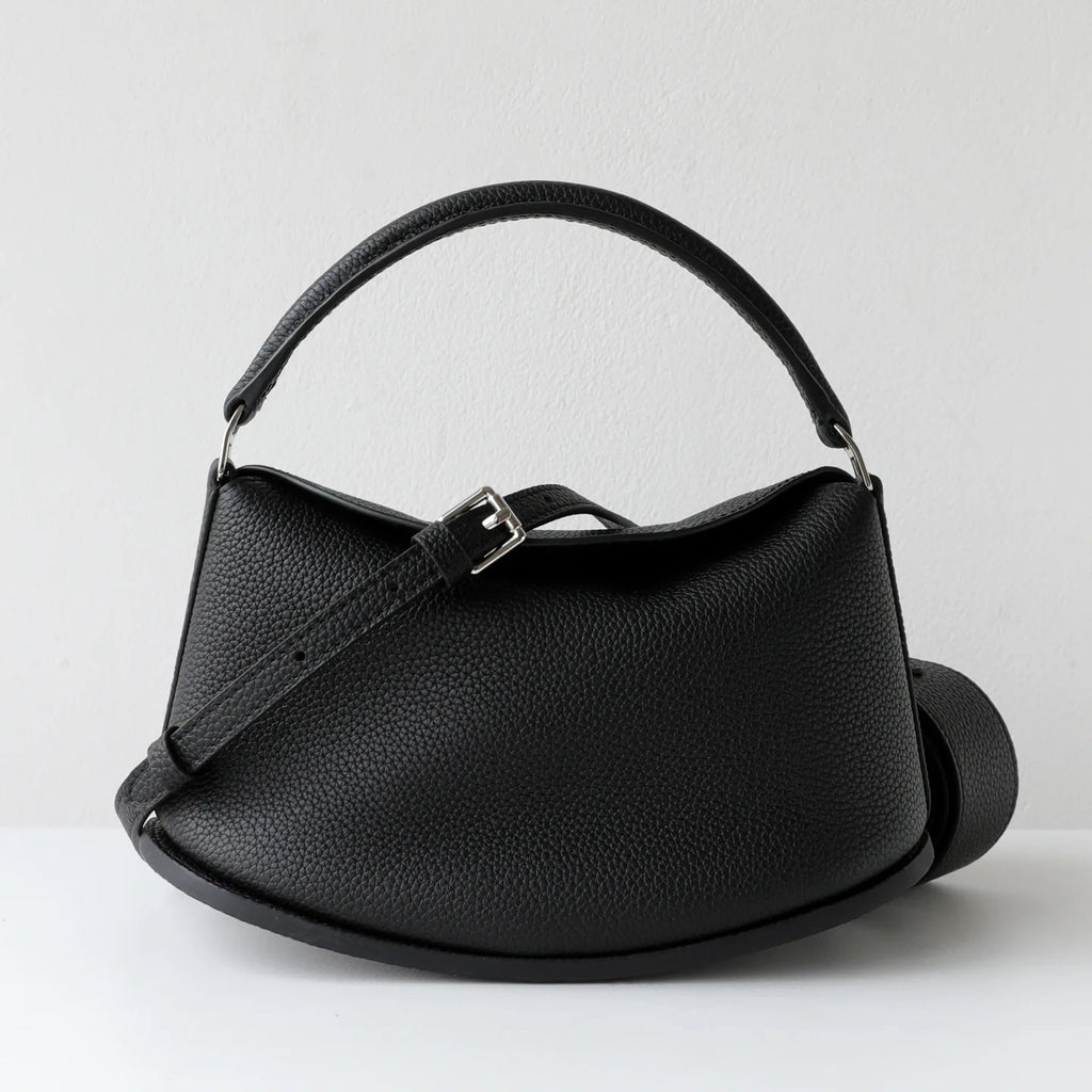 Elegant black pebbled cowhide leather handbag with pillow silhouette, dual straps, and adjustable buckle detail.