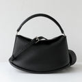 Elegant black pebbled cowhide leather handbag with pillow silhouette, dual straps, and adjustable buckle detail.