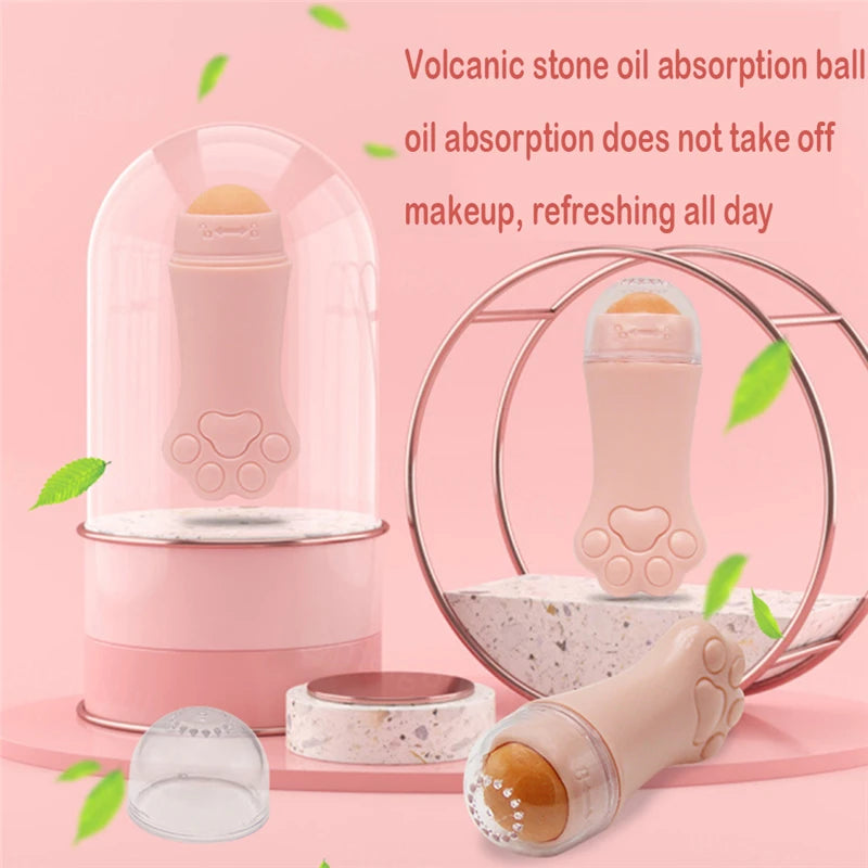 Pink cat paw-shaped facial oil absorbing roller with a volcanic stone ball, displayed with clear covers on a pink base.