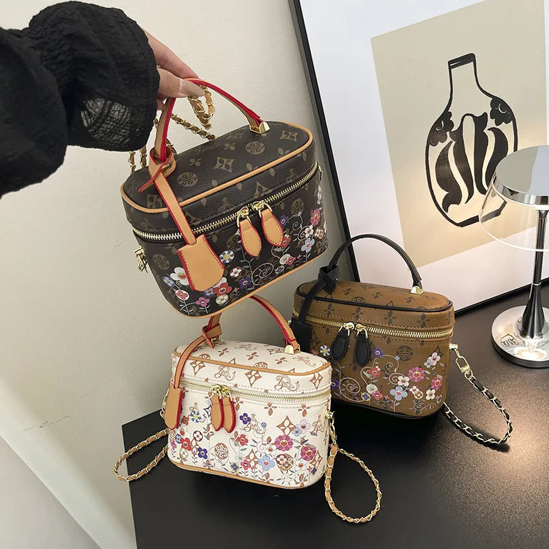 Floral print leather trunk crossbody bags with monogram patterns, top handles, and chain straps in assorted colors.