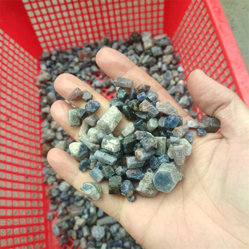Handful of rough blue sapphire crystal gemstones in varying blue tones