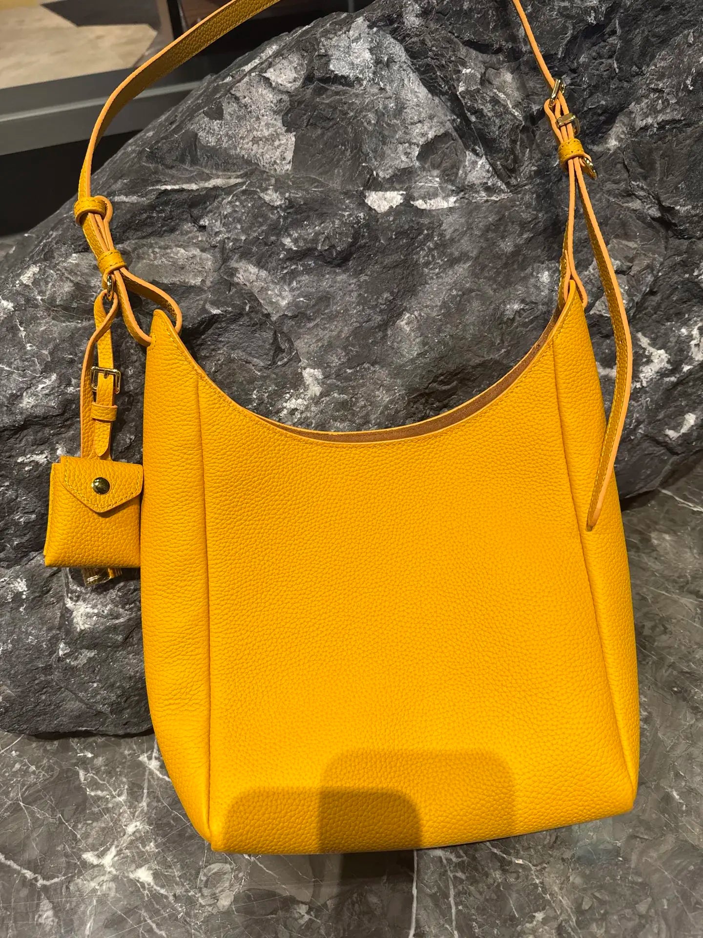 Yellow genuine leather hobo shoulder bag with adjustable strap and small detachable coin pouch charm.
