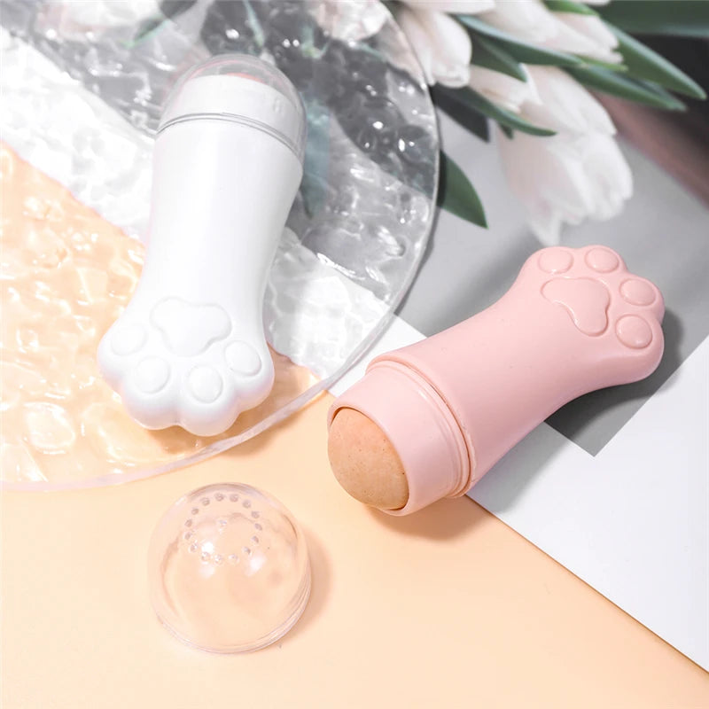 Two cat paw-shaped oil-absorbing rollers with volcanic stone balls, one in white and one in pink with a clear cap.