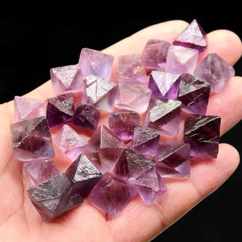 Purple rough crystal octahedra cluster resting in palm, translucent facets and points