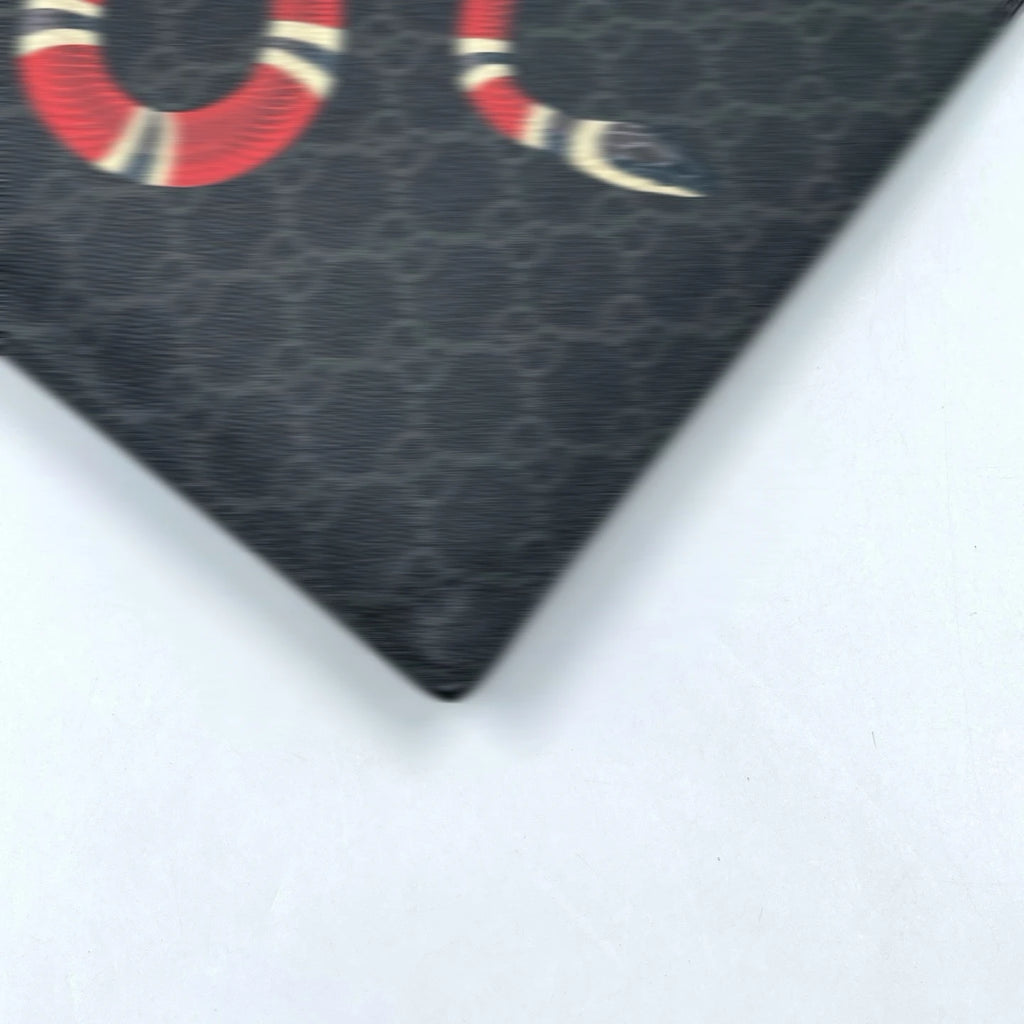 Black canvas designer clutch wallet with iconic GG monogram print and red snake motif. Stylish unisex handheld bag.