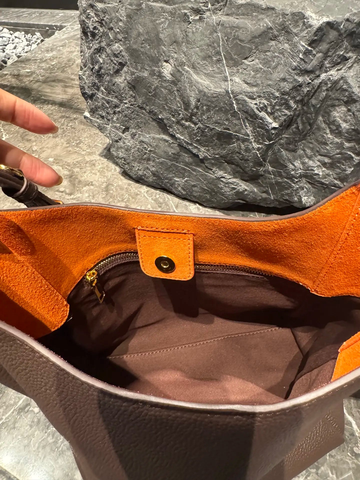 Luxury brown genuine leather hobo bag with contrast orange suede lining, gold snap closure, and brown fabric interior.