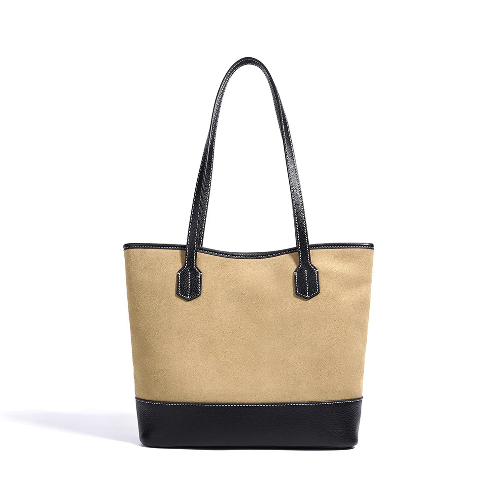 Tan suede tote bag with black leather base, trim, and top handles. Minimalist vintage style for boutique retail.